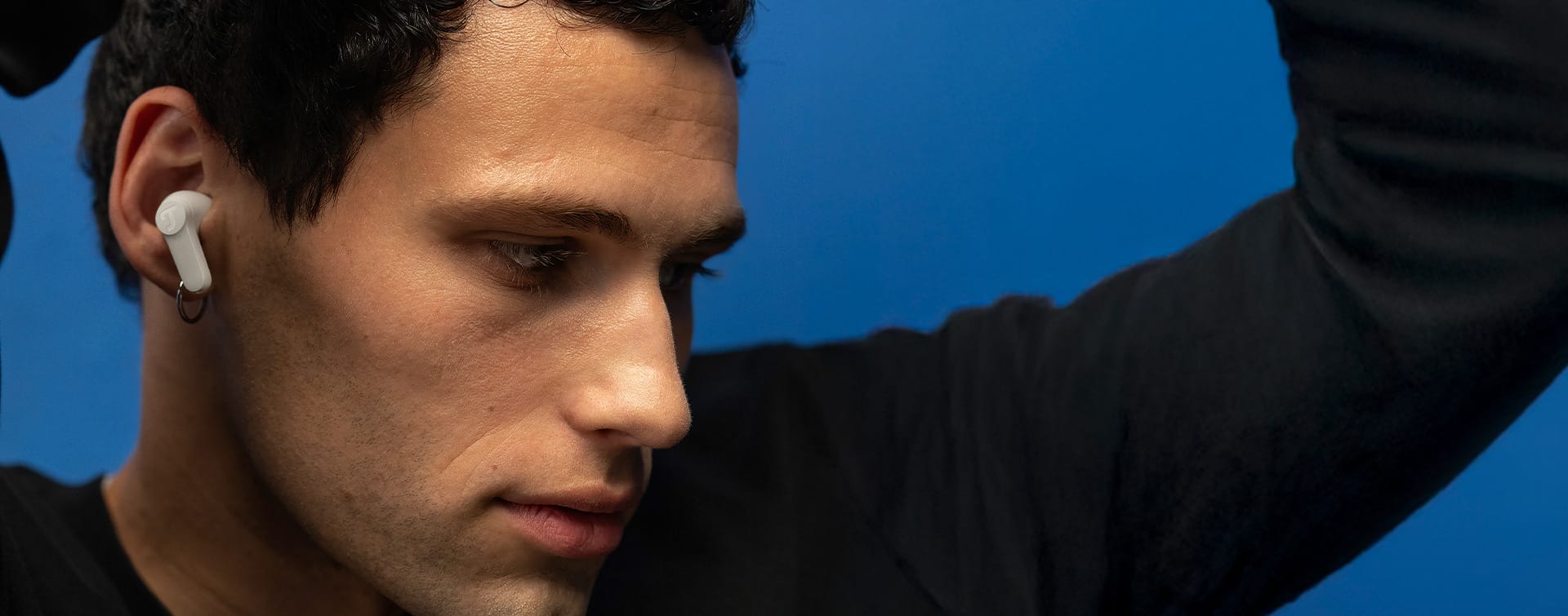 Person mit In-Ear-Kopfhörern bewegt sich zur Musik vor blauem Wand