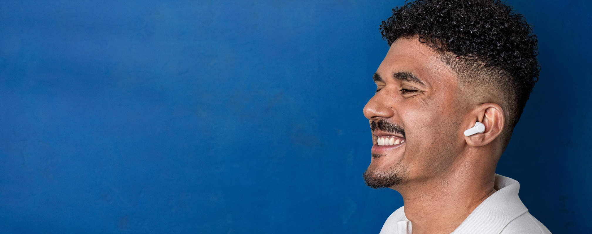 Porträt eines Bankberaters mit In-Ear-Kopfhörern vor blauer Wand