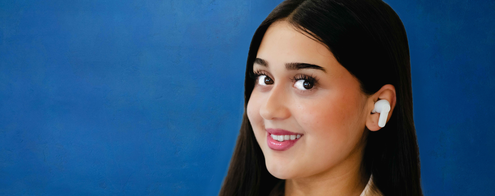 Porträt eines Bankberaters mit In-Ear-Kopfhörern vor blauer Wand