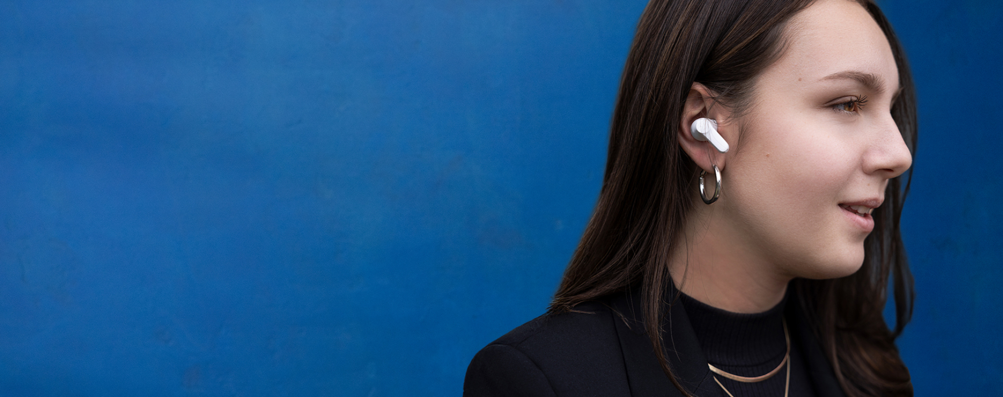 Porträt eines Bankberaters mit In-Ear-Kopfhörern vor blauer Wand