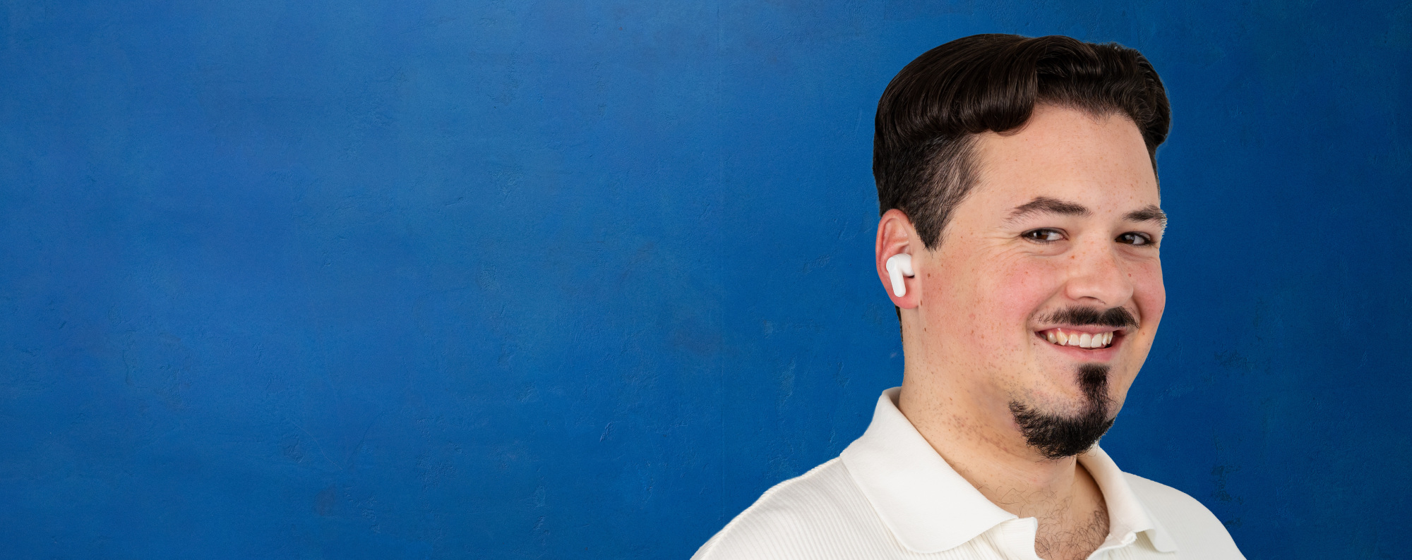 Porträt eines Bankberaters mit In-Ear-Kopfhörern vor blauer Wand